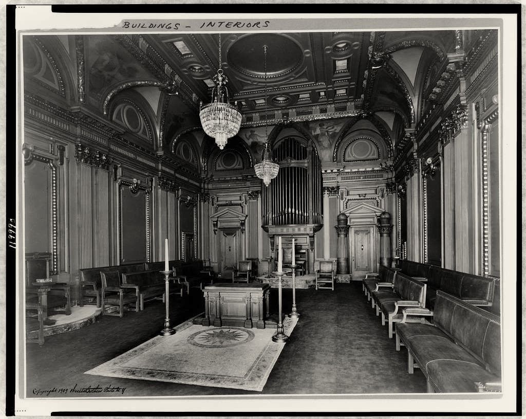 Photograph of an ornate lodge hall with a chandelier, organ, altar and rows of seats along the walls.
