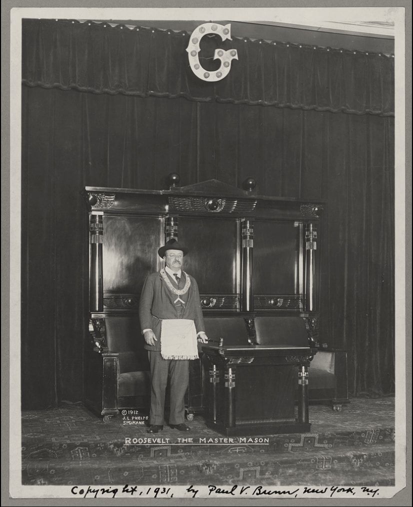 Theodore Roosevelt in Masonic regalia before a master’s chair under the letter G.